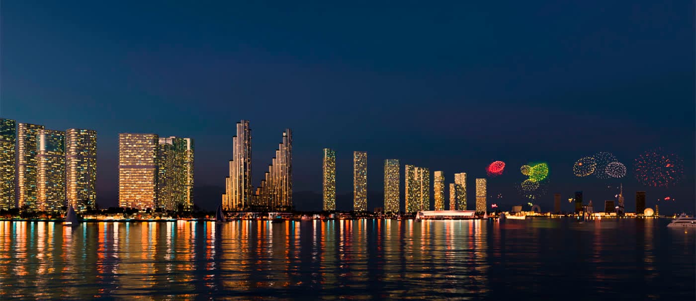 Le front de mer d’Ambassadori Island illuminé à la nuit tombée, vu depuis la mer Noire