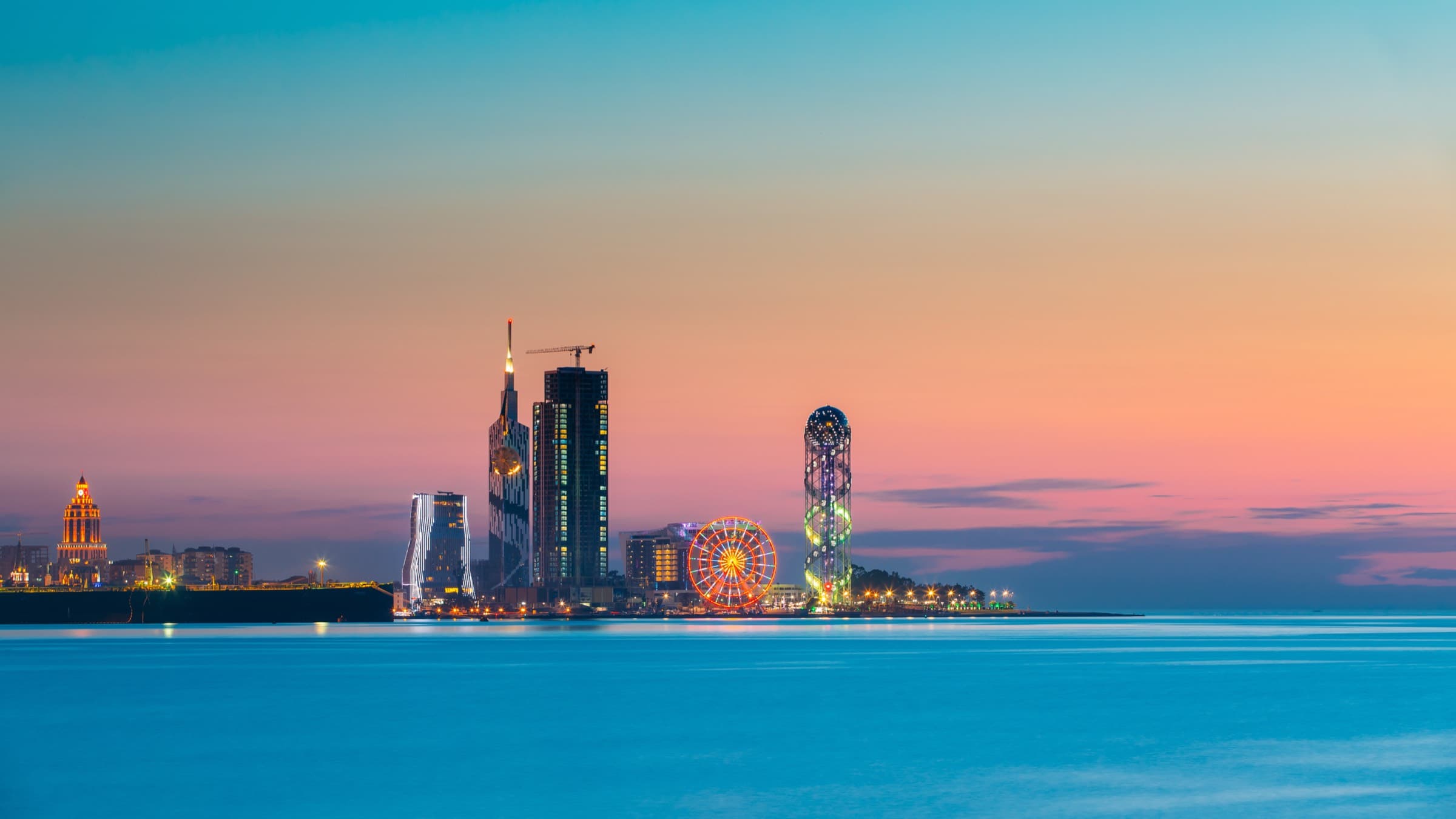 La skyline de Batumi au crépuscule vue depuis la mer Noire, une grue de chantier au milieu des tours