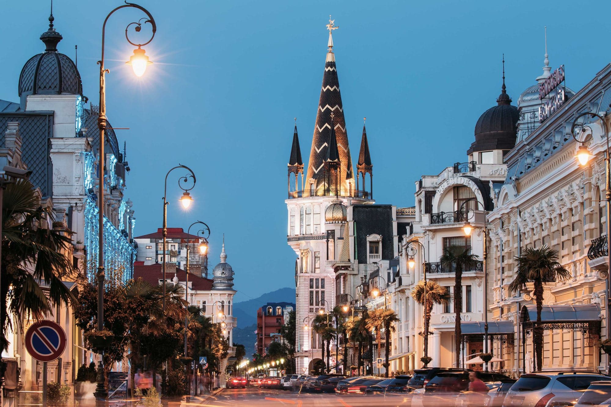 Une rue du Vieux Batumi au crépuscule, façades historiques éclairées et palmiers le long de la chaussée
